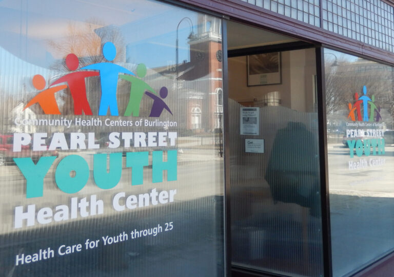 Window Graphics Lettering Glass storefront of Pearl Street Youth Health Center with colorful logo and reflection of a church in the window.