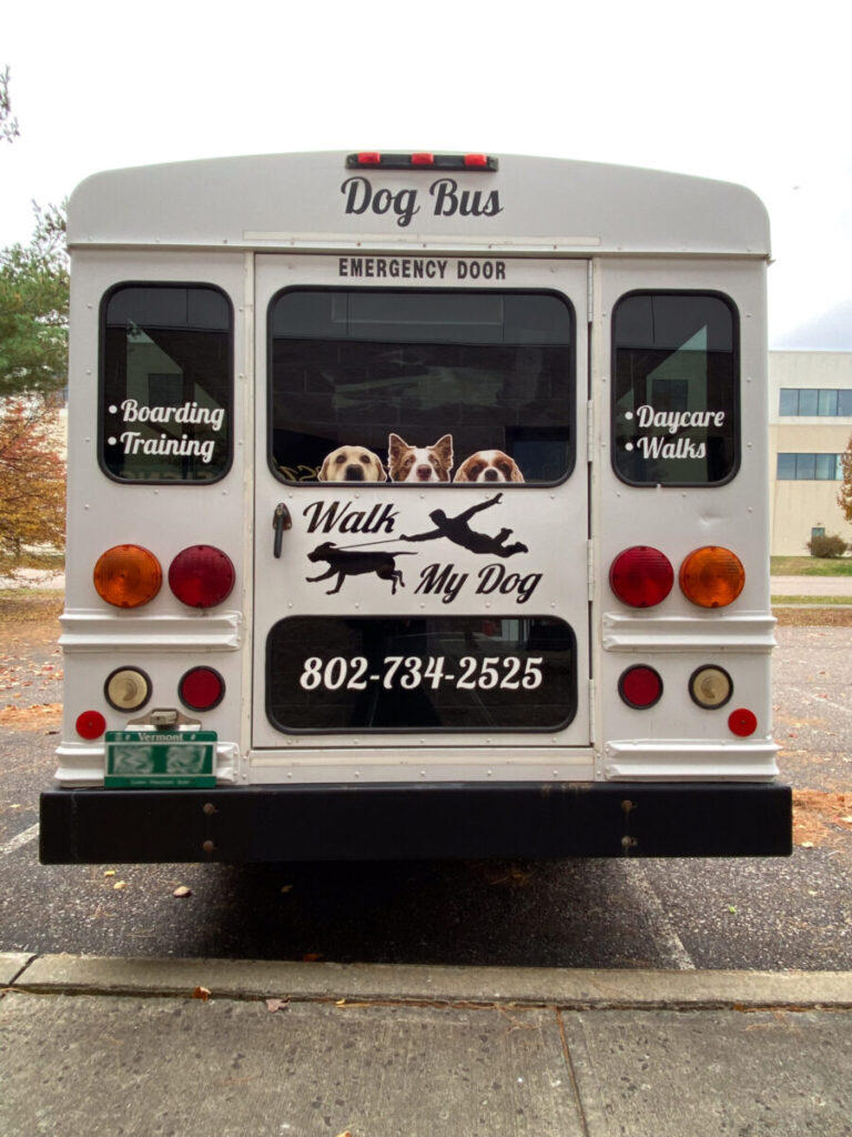 Walk My Dog Logo A white bus labeled "Dog Bus" with three dogs looking out the rear window and business contact information displayed.
