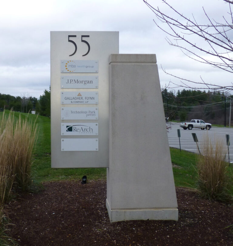 55 Community Drive Monument Sign Outdoor office park sign displaying business names including J.P. Morgan and ReArch, with grass and a road in the background.