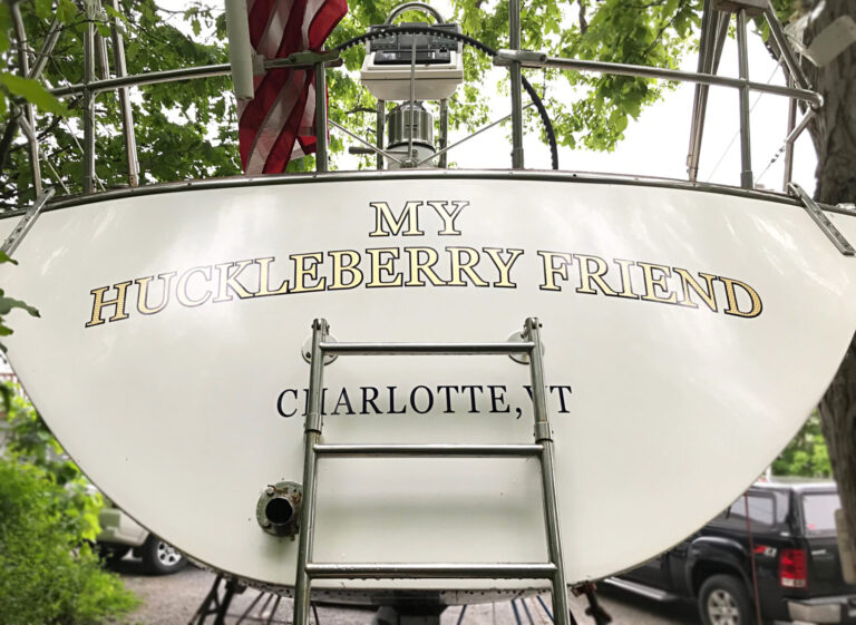 Boat Lettering The stern of a boat displays the name "MY HUCKLEBERRY FRIEND" and "CHARLOTTE, VT" in gold letters.