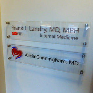 Timberland Physical Glass Two clear office nameplates on a wall for Frank J. Landry, MD, MPH, and Alicia Cunningham, MD.