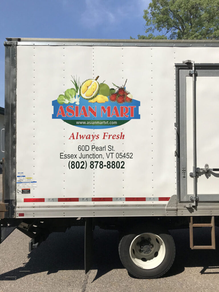 Asian Mart Truck Asian Mart delivery truck with store logo, address, and contact number on the side, parked in daylight.