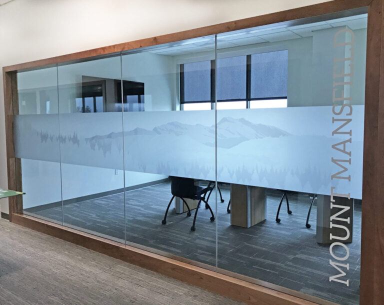 Office meeting room with glass wall featuring a frosted mountain design and the words "Mount Mansfield" on the glass.
