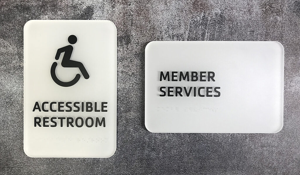 ADA Custom Signage Two white signs: one reads "Accessible Restroom" with a wheelchair symbol, the other reads "Member Services.