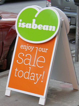 Isabean Sale Sign A sidewalk sign reads "isabean enjoy our sale today!" with a green and orange color scheme.