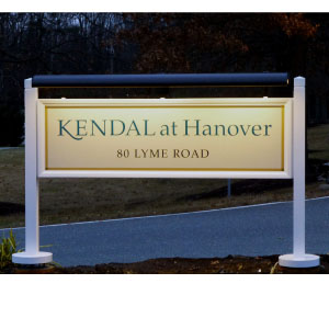 Kendal at Hangover Community Illuminated sign reads "KENDAL at Hanover, 80 LYME ROAD" beside a road with trees in the background.
