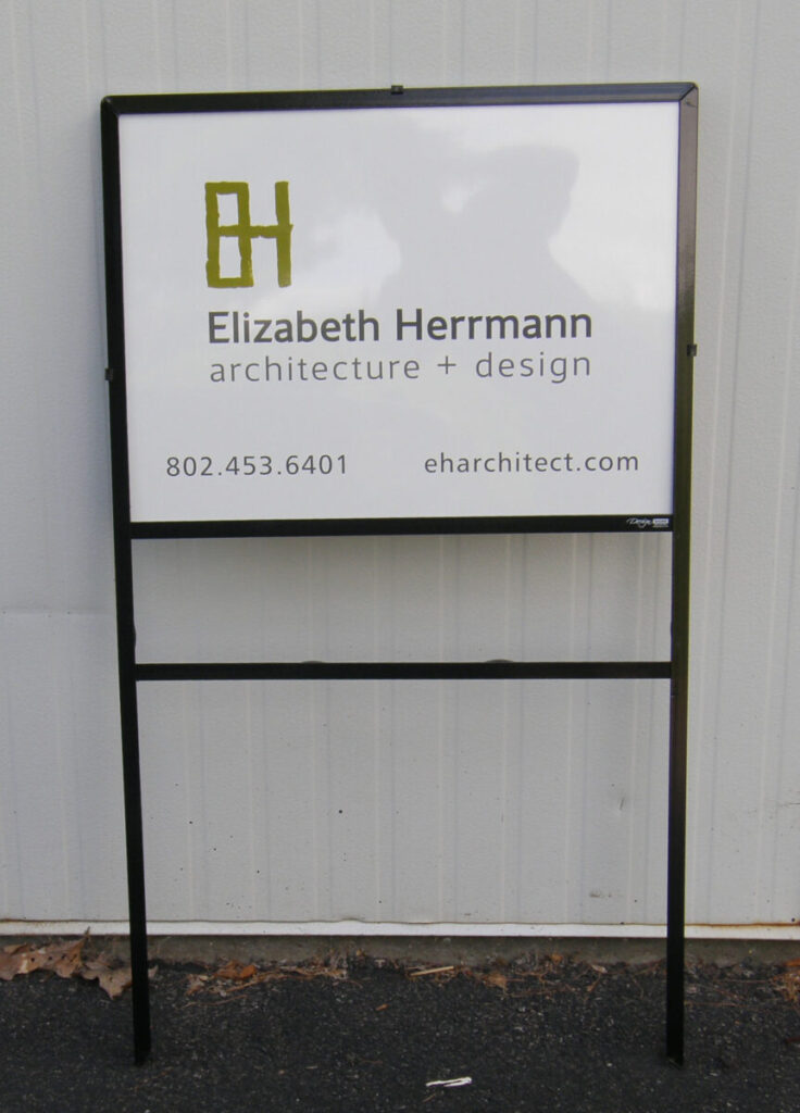 Basic Real Estate Marketing Sign A sign for Elizabeth Herrmann Architecture + Design with contact info, standing against a white wall.