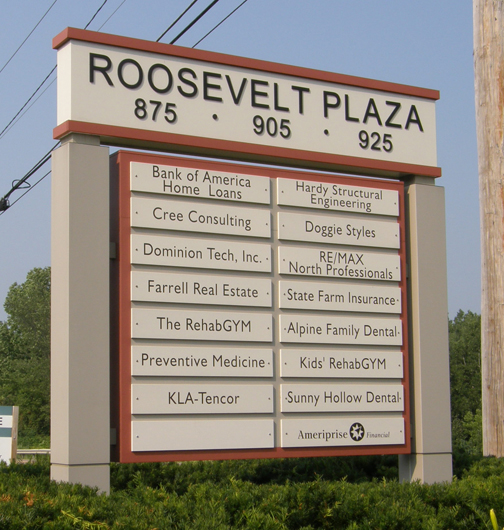 Roosevelt Plaza Directory Shopping plaza sign listing various businesses, including banks, gyms, dental offices, and consulting services.
