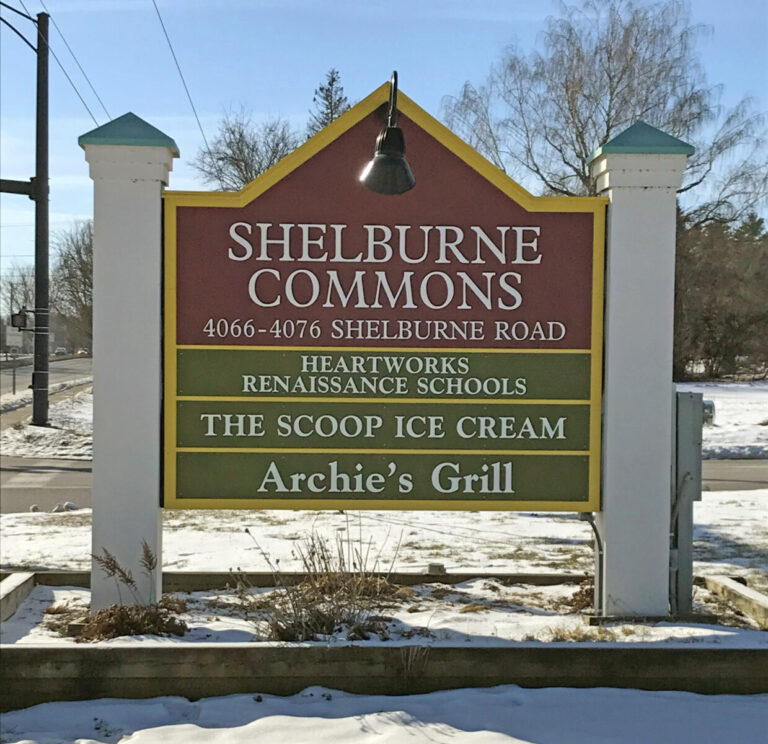 Shelburne Commons A sign for Shelburne Commons listing Heartworks Renaissance Schools, The Scoop Ice Cream, and Archie's Grill.