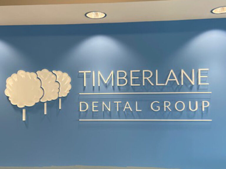 Timberland Dental Group Wall with "Timberlane Dental Group" sign and three tree icons on a blue background.