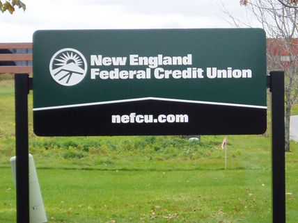 New England Federal Credit Union Sign for New England Federal Credit Union with web address nefcu.com displayed on a grassy lawn.