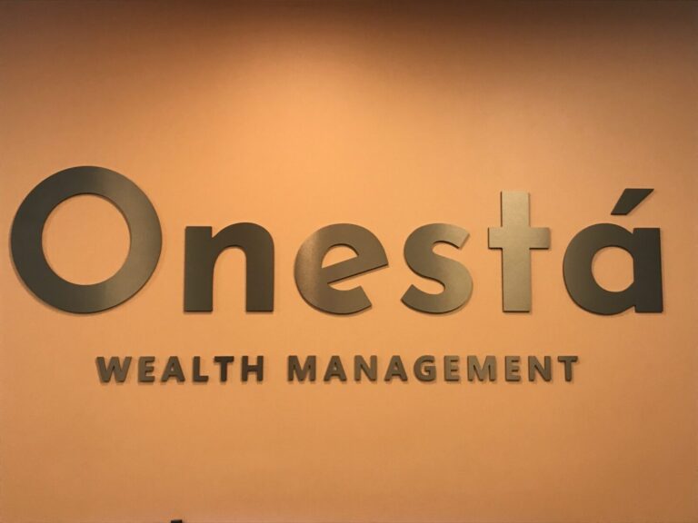 Onesta Raised Letters Onestá Wealth Management sign displayed on a plain orange wall.